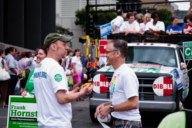 Rep. Jim Davnie speaks with Tim Stanley at Twin Cities Pride with the DFL truck in the background.